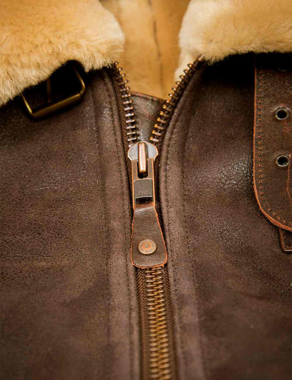 Close-up of a brown leather jacket with a zipper and fur lining.