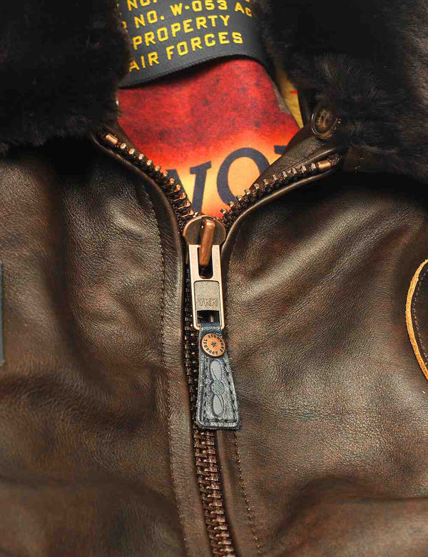 Metal zipper on a men's brown leather jacket with a fur collar.