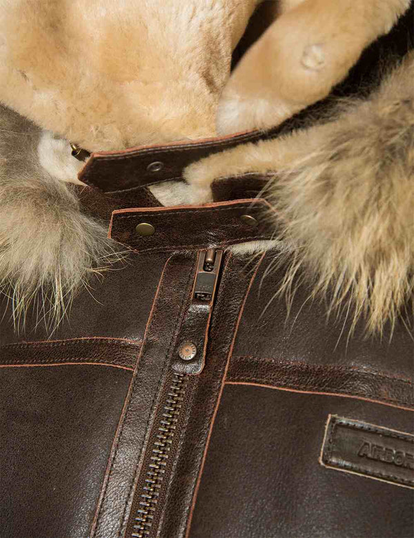 Fastening on a brown fur jacket with a hood.