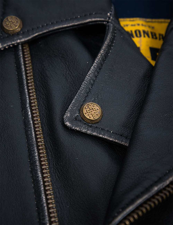 Buttons on the collar of a black leather jacket.