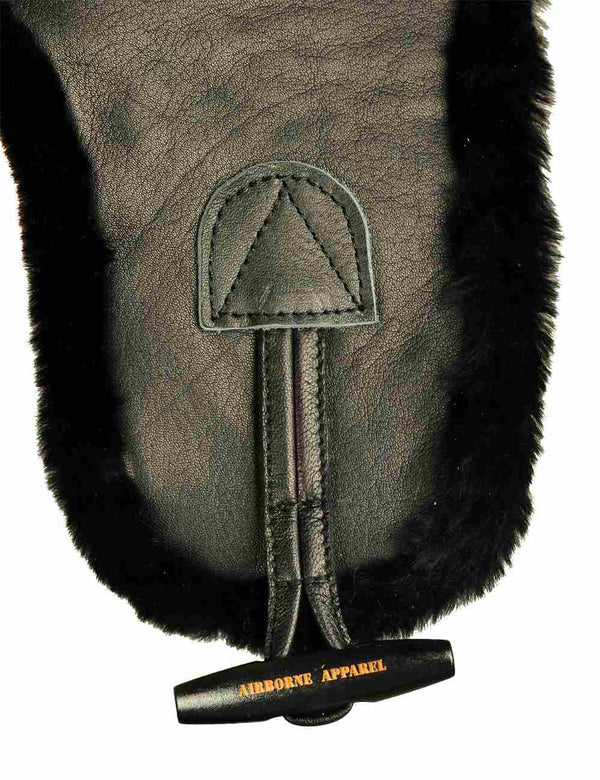 A horn wooden button on a black leather trapper hat.