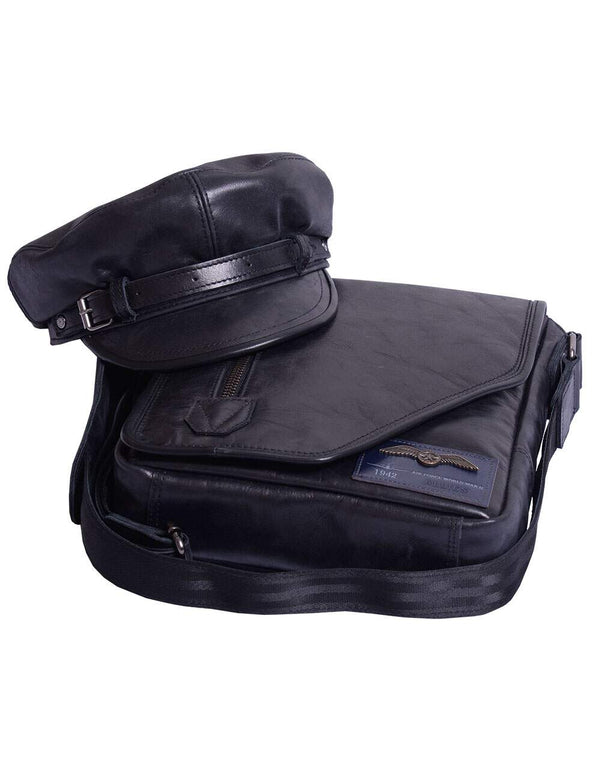A men's black leather cap is placed on top of a men's leather bag.