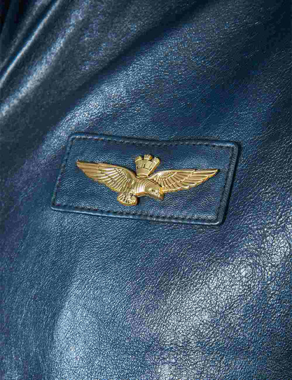 A patch with metal wings on the chest of a dark blue men's leather jacket.