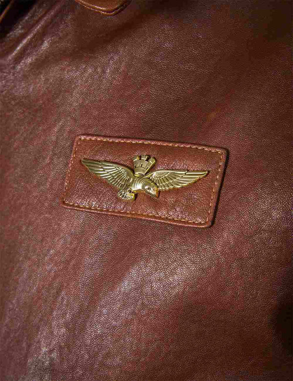 Metal wings patch on the chest of a men's brown leather jacket.