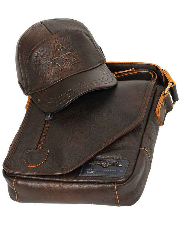 A brown leather cap is placed on top of a men's leather bag.