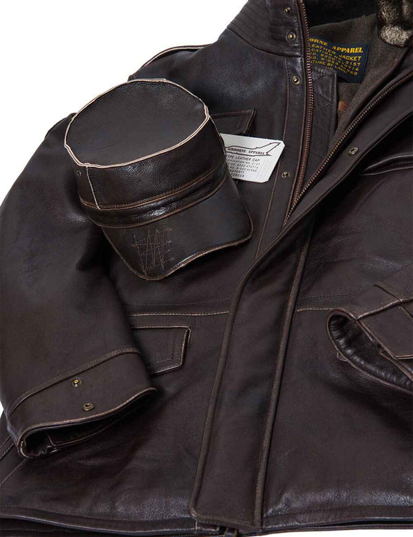 A brown men's leather cap is placed on a brown leather jacket.