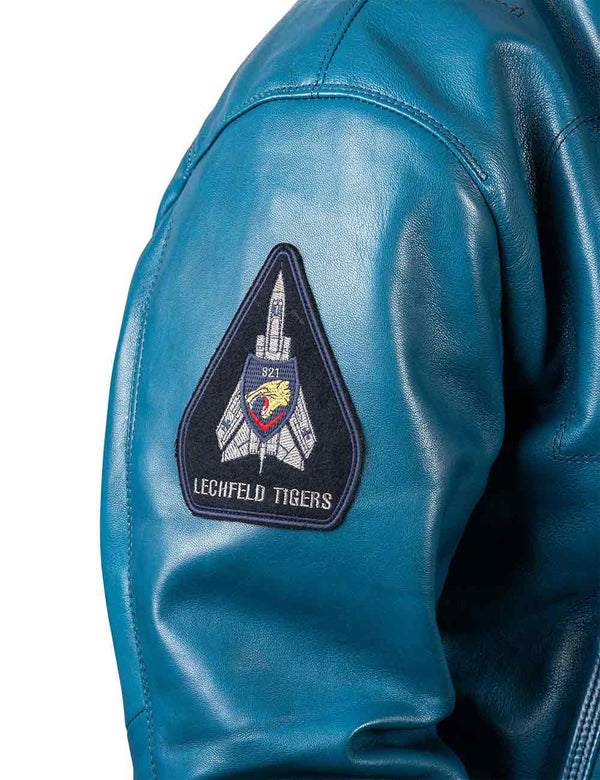 A patch with the image of a military aircraft on the right sleeve of an lagoon blue leather jacket.