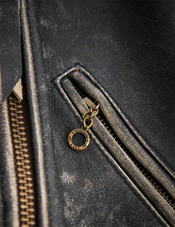 Metal zipper on the pocket of a black women's leather jacket with bleached seams.