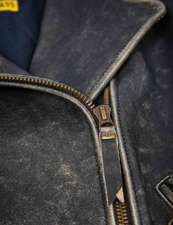 A metal zipper puller on a black women's leather jacket with bleached seams.