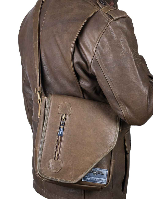 A men's olive leather shoulder bag is worn over an olive leather jacket.