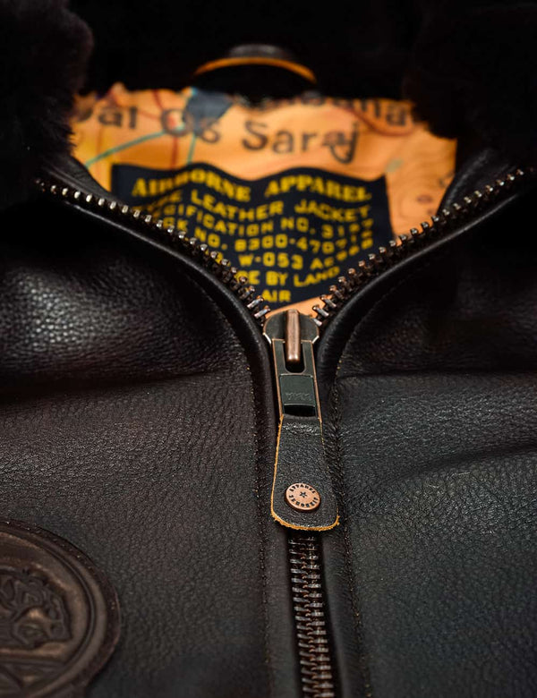 Metal zipper on men's brown leather jacket with patches.