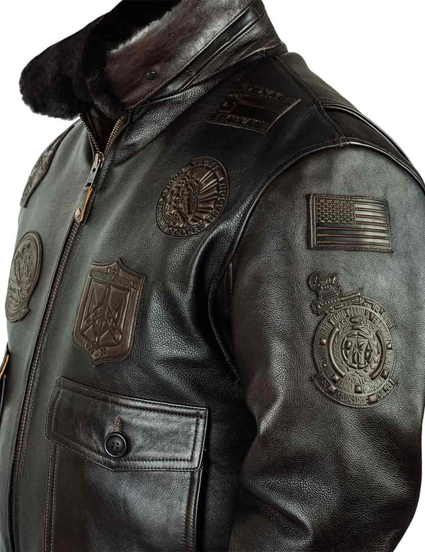 Top of a men's brown leather jacket with patches and a raised fur collar, viewed slightly from the side.
