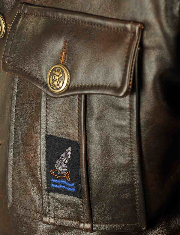 A pocket with a patch on the chest of a men's brown leather coat.