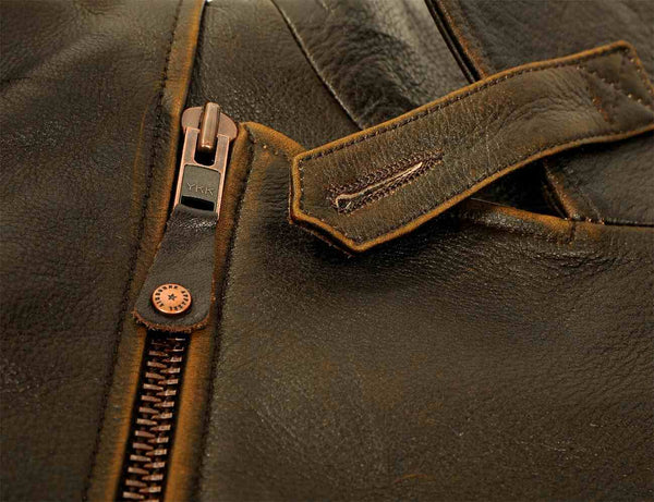 A metal zipper puller of a men's brown leather biker jacket.