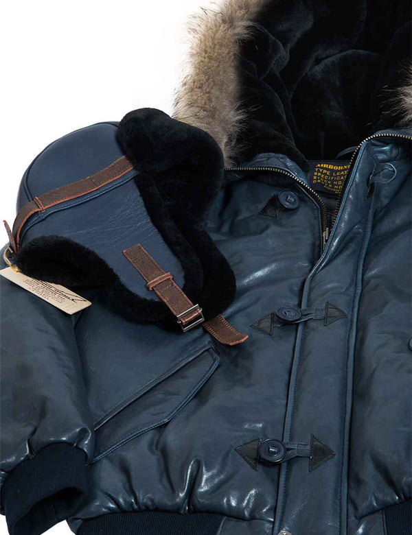 Men's blue short leather parka with a hood trimmed with raccoon fur, with a blue sheepskin ushanka on top.