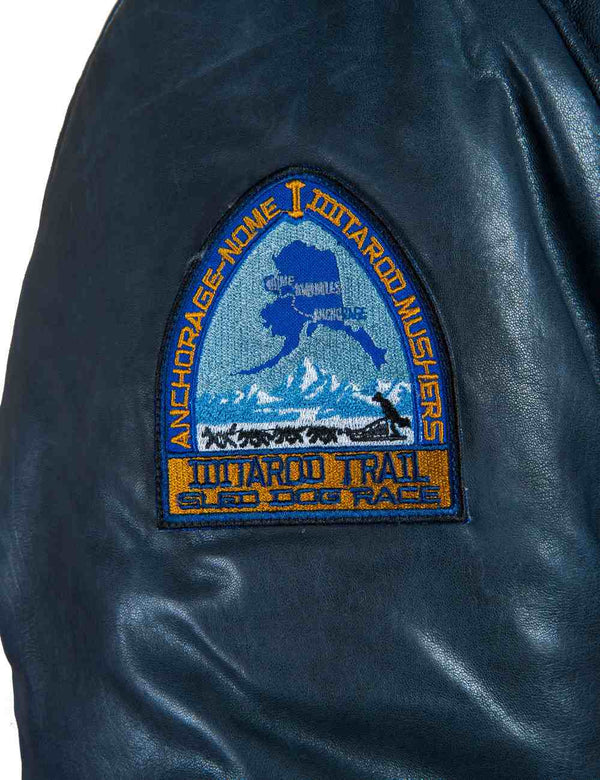 A bright patch on the sleeve of a men's blue short leather parka.