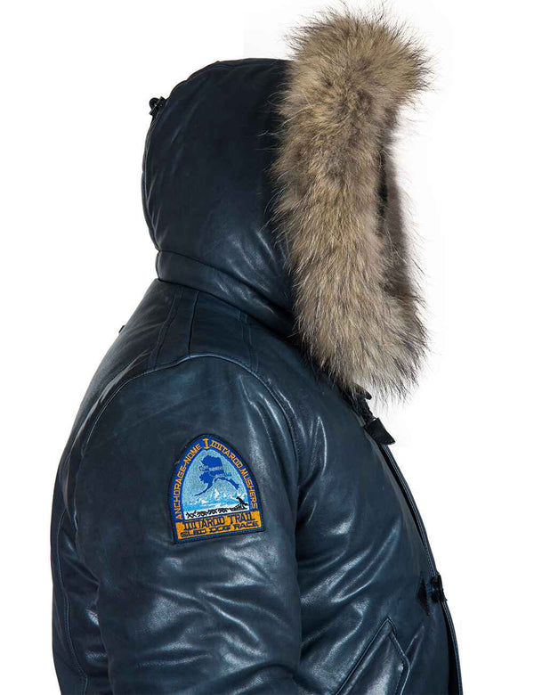 Side view of the top of a men's blue leather parka with a raccoon fur trimmed hood.