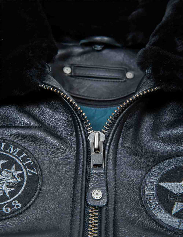 A metal zipper on a men's black leather jacket with fur a collar and patches.