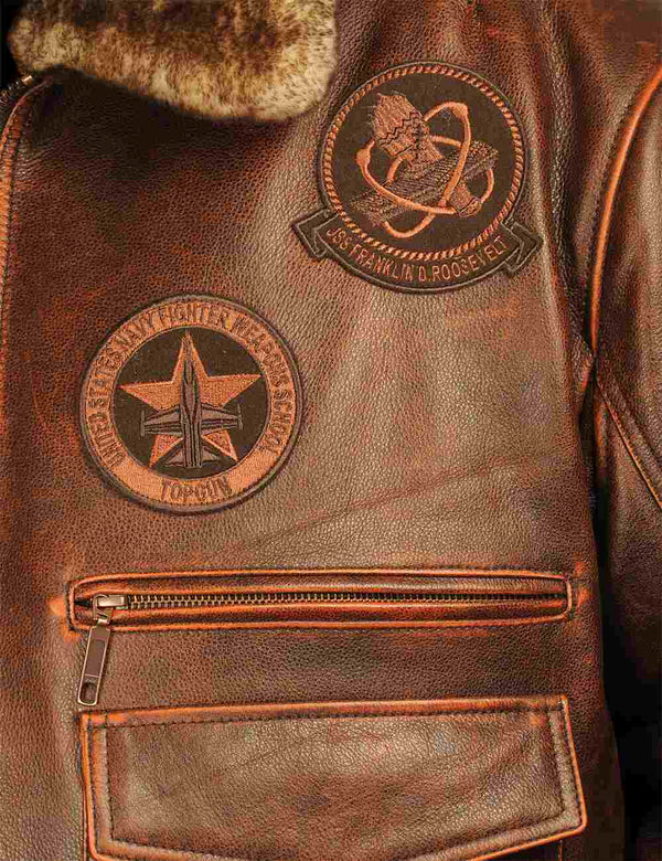 Patches on the chest of a men's brown leather jacket with a fur collar.