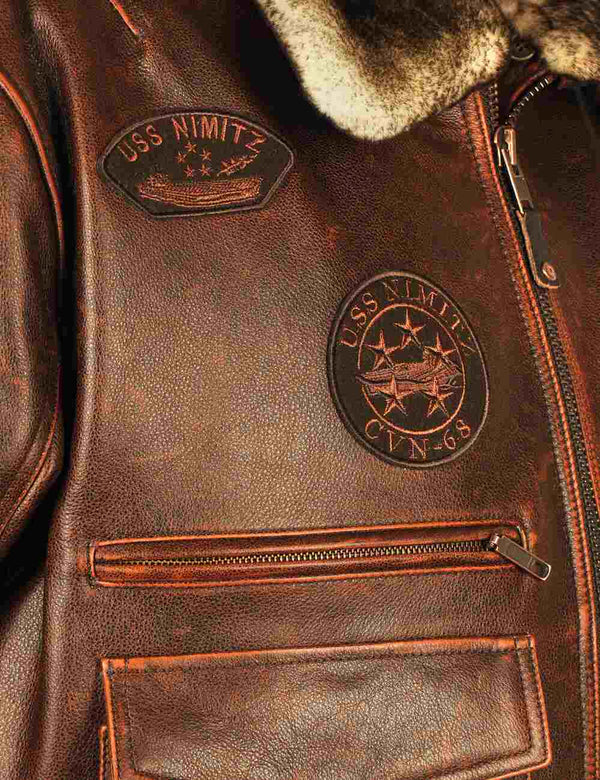 Patches on the chest of a men's brown leather jacket with a fur collar.