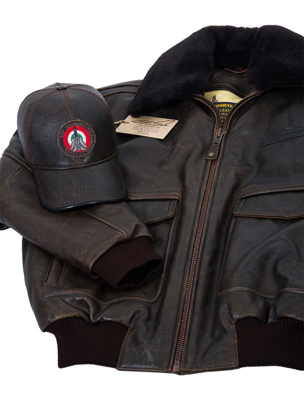 A men's brown leather baseball cap with a bright patch on the forehead is placed over a short brown leather jacket with a sheepskin collar.