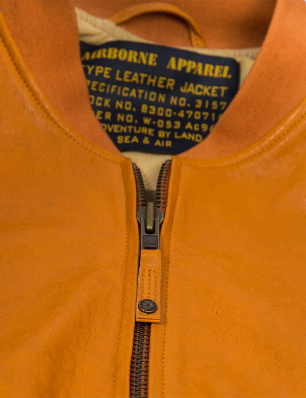 Metal zipper on men's orange leather jacket with elastic band.