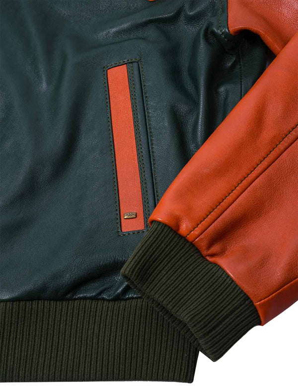 Bottom left side of a men's dark green leather jacket with an orange sleeve and pocket trim.