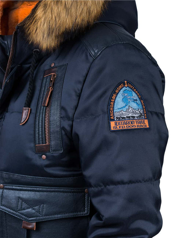 Patch on the left sleeve of a men's dark blue jacket with a hood trimmed with raccoon fur.