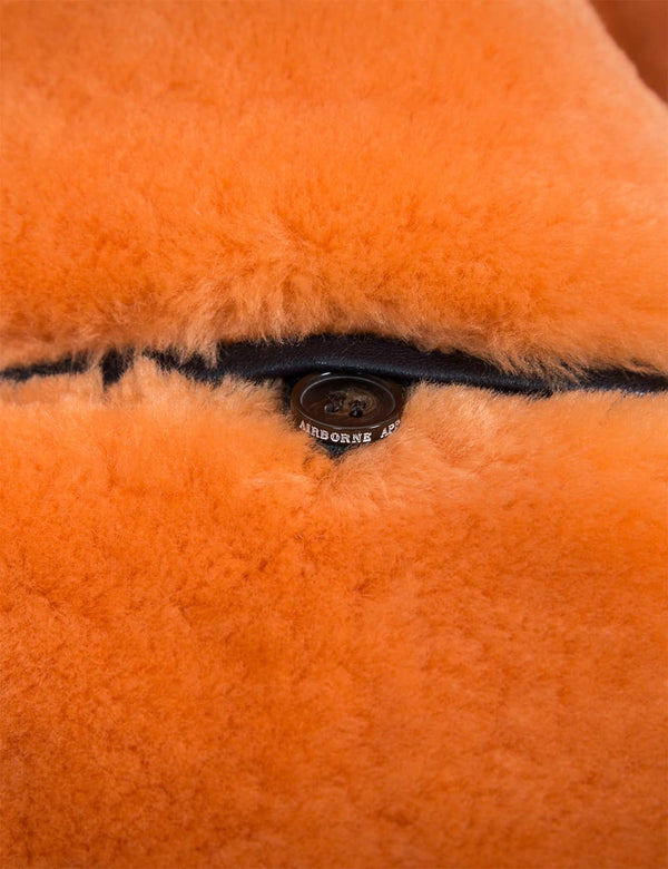 An internal button pocket on an orange fur lining of a men's jacket.