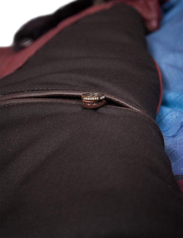 A button on the inside pocket of a men's burgundy leather vest.