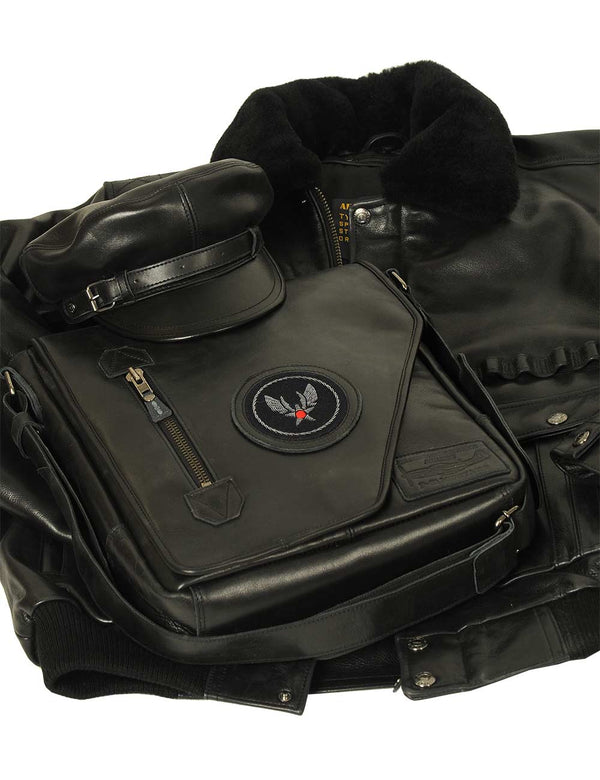 A composition of a men's black leather cap and a bag, which lie on top of a men's leather jacket with a fur collar.