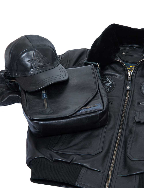 A composition of a black men's cap with embossing and a bag, which are placed on top of a black leather men's jacket with a fur collar.