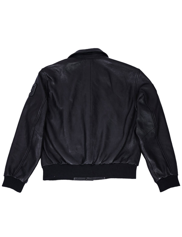 A leather black jacket with an elastic waistband and a patch on the left shoulder on a white background, back view.