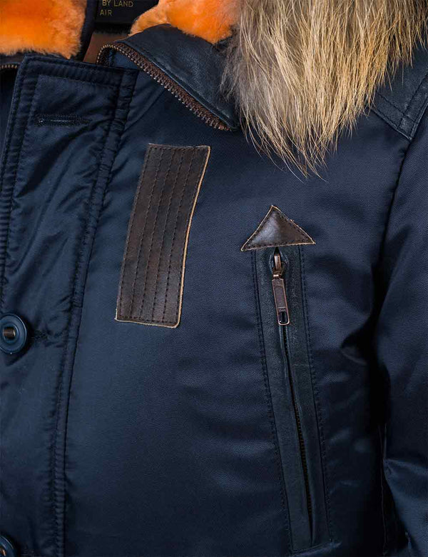 Chest pocket on a dark blue men's parka with a hood trimmed with raccoon fur.