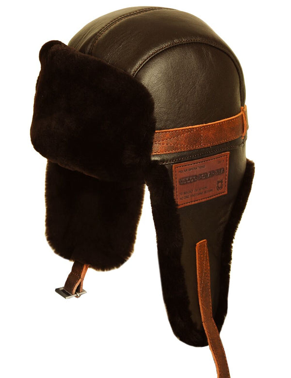 Men's brown leather trapper hat with patch and sheepskin lining, slight twist.