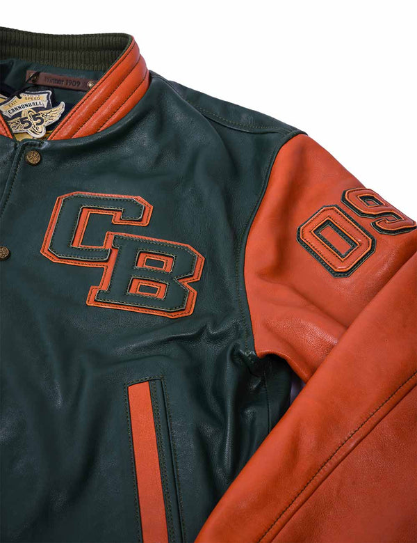 The upper left side of a dark green leather men's jacket with an orange sleeve and collar. There are also patches on the chest and shoulder.